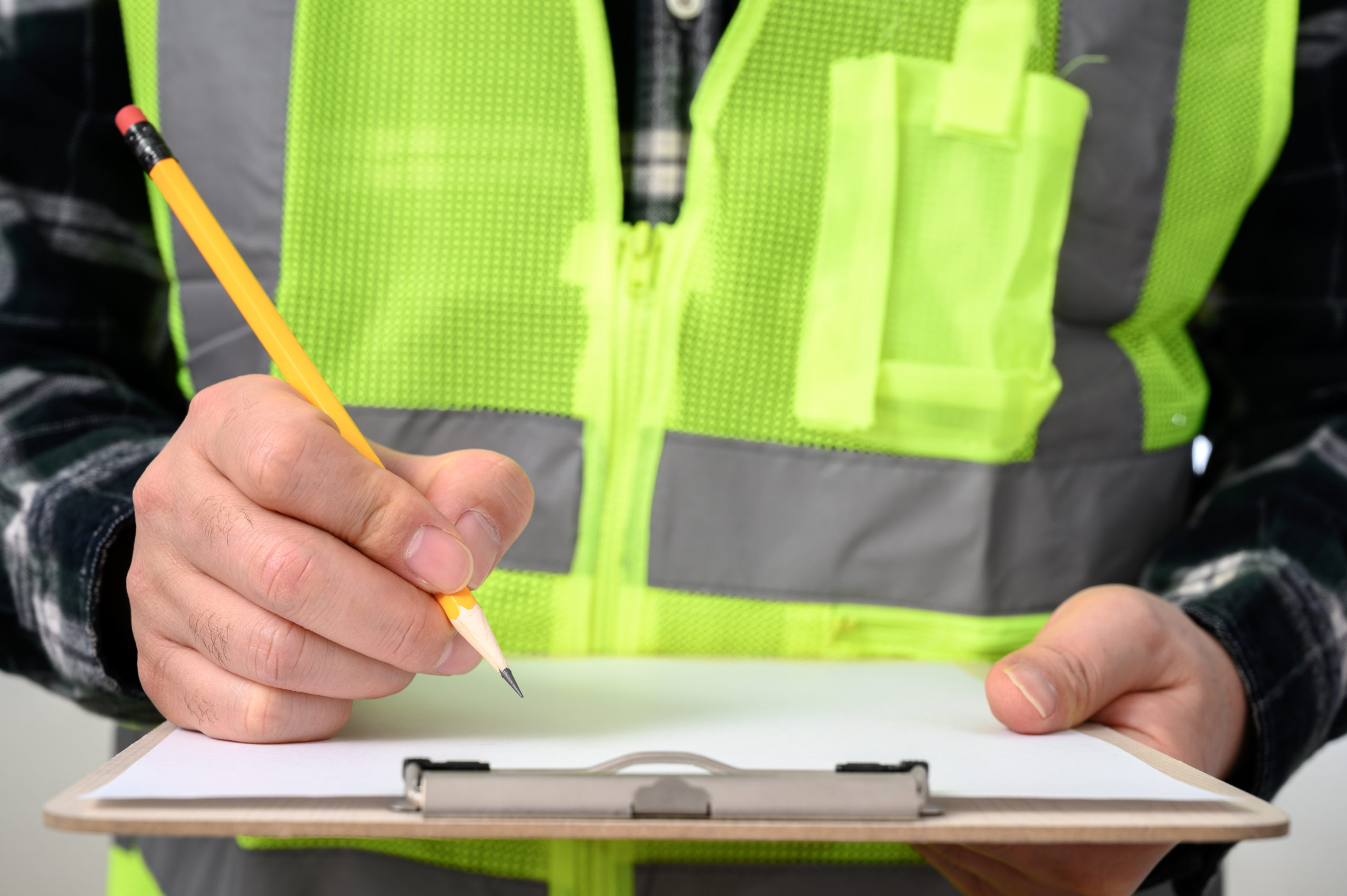 A close-up of a man's hand signing a document with a clipboard.